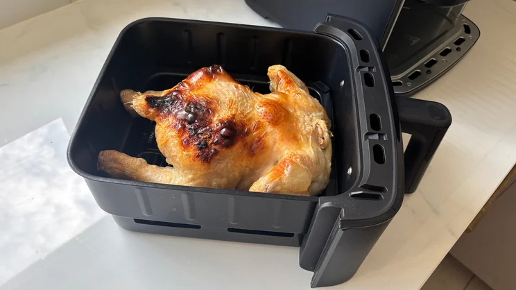 A cooked chicken in the Bosch Series 6 Double Stack Drawer Air Fryer's drawer, removed from the appliance