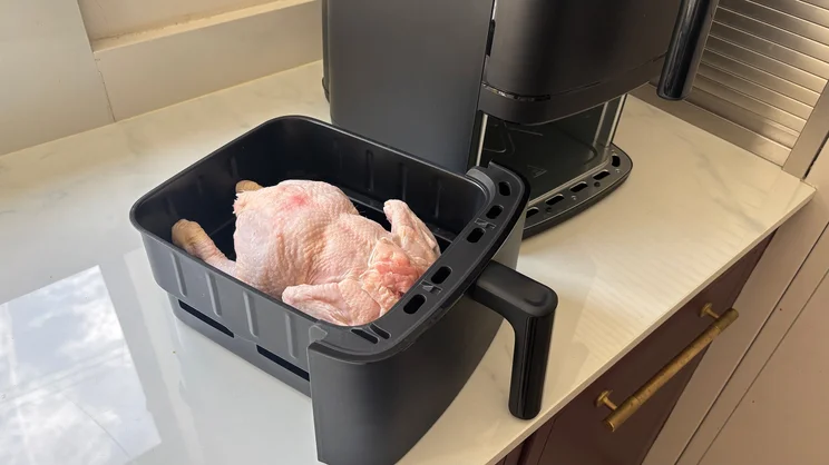 A bird's eye view of an uncooked chicken in the open drawer of the Bosch Series 6 Double Stack Drawer Air Fryer