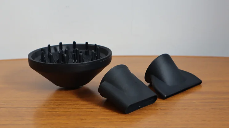 The Cloud Nine Airshot Pro Adapt hair dryer's attachments, on a wooden table