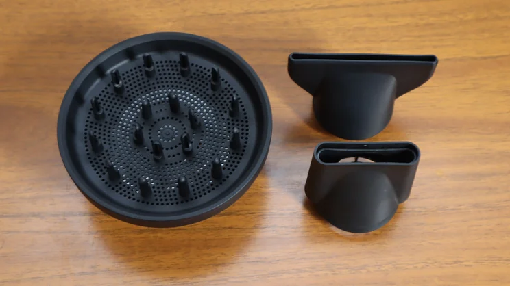 A bird's eye view of the Cloud Nine Airshot Pro Adapt hair dryer's attachments, on a wooden table