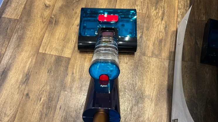 Top-down view of the Dyson Clean and Wash Hygiene cleaner head and clear water tank with its blue cap and red release button