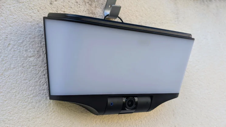 Eufy S4 4K Solar Wall Light mounted on a rendered outdoor wall, viewed from below at an angle, showing the frosted light panel and the camera with a blue indicator light.