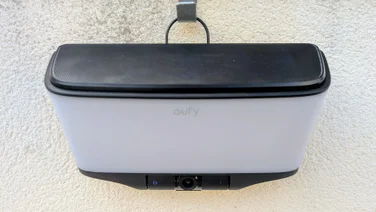 Front view of the Eufy S4 4K Solar Wall Light mounted on a wall with the solar panel clipped on top, the eufy logo on the frosted panel and the camera with a blue indicator ring below.