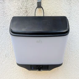Front view of the Eufy S4 4K Solar Wall Light mounted on a wall with the solar panel clipped on top, the eufy logo on the frosted panel and the camera with a blue indicator ring below.