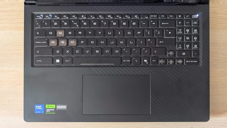 Top-down view of the MSI Raider 16 HX UK keyboard deck with numpad, clear WASD keycaps, touchpad and Intel Core Ultra 7, GeForce RTX and HDMI badges