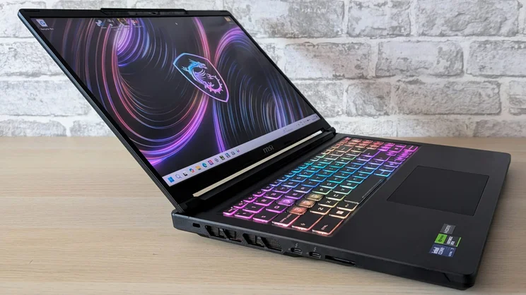 Low left-side angle of the open MSI Raider 16 HX, showing the display, RGB keyboard, side vents and Thunderbolt ports