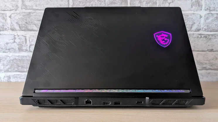 Rear of the MSI Raider 16 HX with a glowing purple MSI logo on the lid, a rear RGB light bar, Ethernet, HDMI and USB ports and exhaust vents