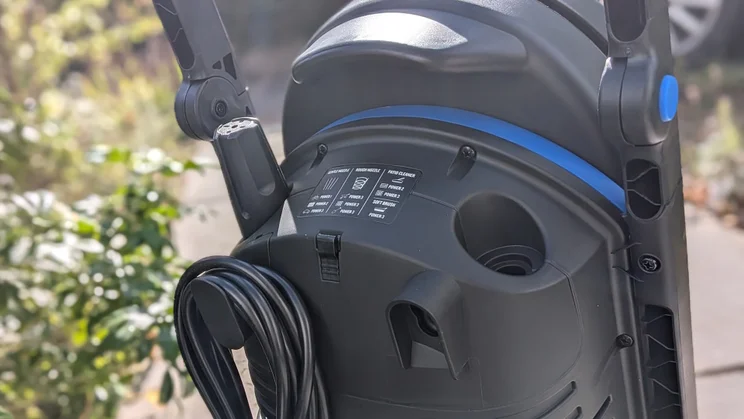 Back of the Nilfisk Core 150 PowerControl showing the cable wrapped on its hook, a nozzle holder and a label listing power settings for each nozzle.