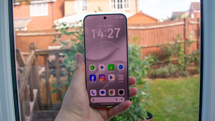 Oppo Find X10 Pro Max in hand, front view with the display on, in front of a window