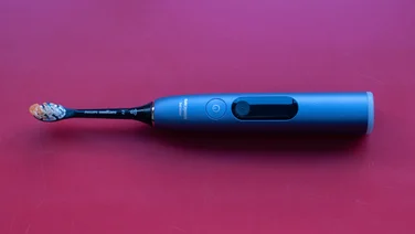 A bird's eye view of the Philips Sonicare DiamondClean 9900 Prestige electric toothbrush, laying on a red table