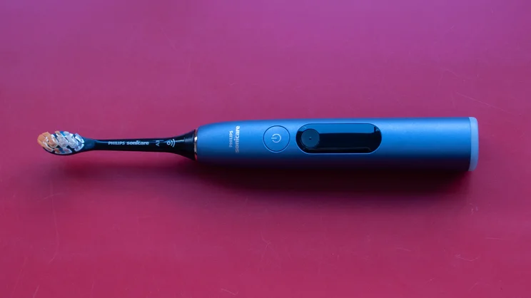 A bird's eye view of the Philips Sonicare DiamondClean 9900 Prestige electric toothbrush, laying on a red table