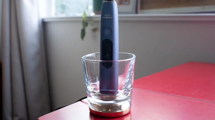 The Philips Sonicare DiamondClean 9900 Prestige electric toothbrush sitting its charging glass base