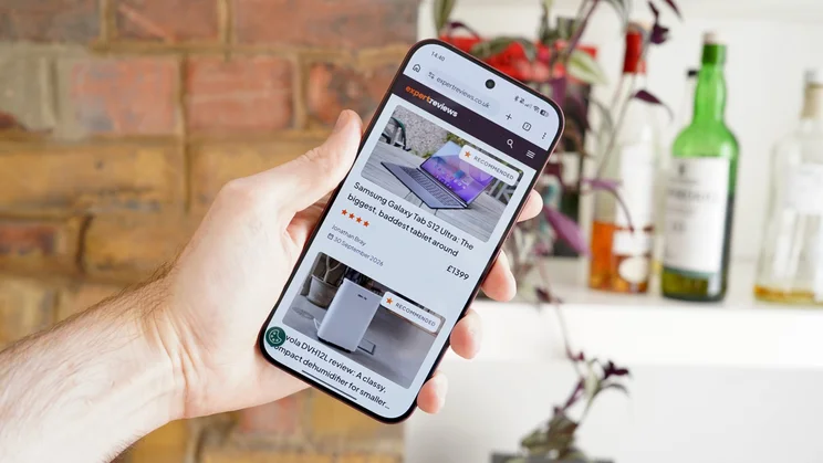 Poco F9 Ultra in hand, displaying Expert Reviews homepage