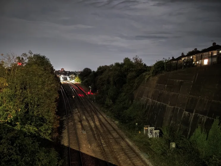 Train tracks at night, viewed from a bridge
