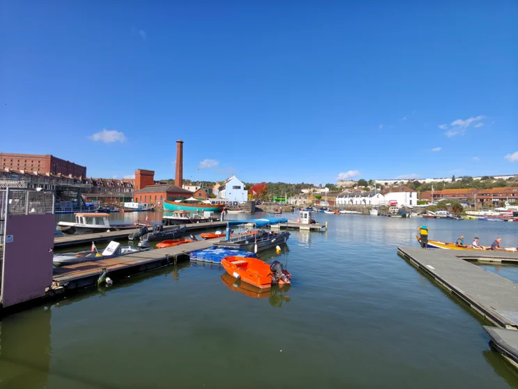 Wide-angle shot of a marina with boats docked and buildings in the distance