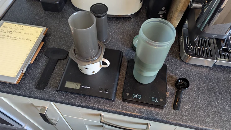 A bird's eye view of the AeroPress Original and the Wacaco Prestina, being used side by side on a kitchen counter
