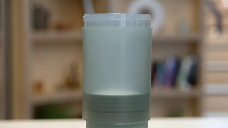 A closeup of the Wacaco Prestina coffee maker, standing upright on an office table