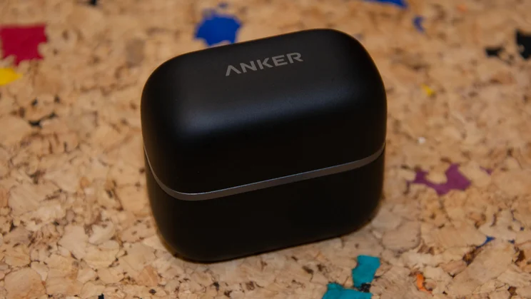 The closed black pebble-style charging case for the Anker Soundcore AeroClip 2 clip-on earbuds, showing the printed Anker logo and subtle grey accent band