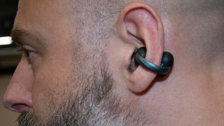 Side profile of a man wearing the black Anker Soundcore AeroClip 2 clip-on earbud, demonstrating how the curved bridge hooks comfortably around the outer ear cartilage