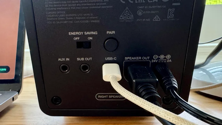 Close-up of the rear connection panel on the right Creative XF1 desktop speaker, showing ports for AUX IN, SUB OUT, USB-C, SPEAKER OUT, and power input with connected cables