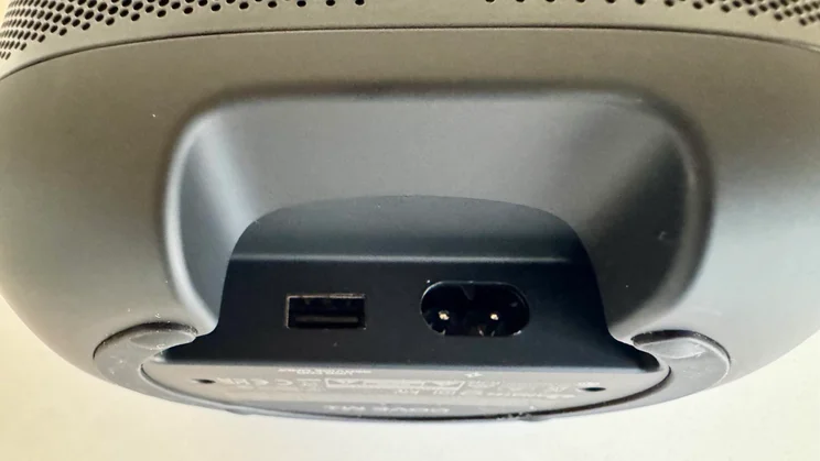 Recessed connection panel beneath the JBL Cove M1 wireless speaker, featuring a USB port and a two-pin mains power input socket