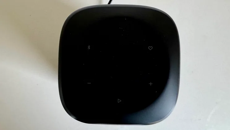 Overhead view looking directly down onto the top control surface of the JBL Cove M1 wireless speaker, showing playback, volume, and connectivity touch controls