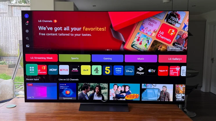 Direct front view of the webOS home screen interface on the 77in LG C6 OLED TV featuring Primary RGB Tandem OLED technology, displaying app shortcuts, content recommendations, and banner promotions