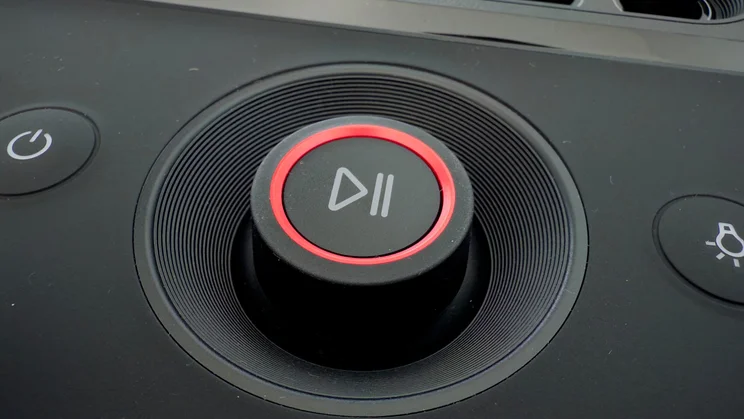A close-up view of the central play/pause dial on the LG xboom Stage 501, encircled by a glowing red LED ring