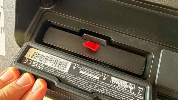 A hand partially inserting or removing the swappable battery pack from the battery compartment of the LG xboom Stage 501 speaker