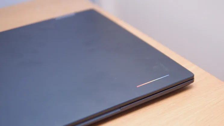 Close-up of the closed Acer Googlebook 14 lid with a thin multicoloured Google accent line near the corner, on a wooden desk.