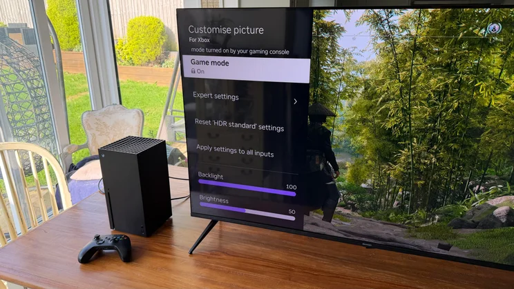 Front angled view of the Sharp HJ6725KB Roku TV displaying the "Customise picture" settings menu with "Game mode On" next to an Xbox Series X console