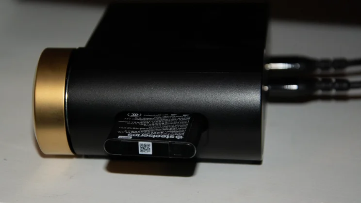 Side profile of the SteelSeries Arctis Nova Elite gaming headset's GameHub base station, showing a removable lithium-ion battery inserted into its side charging slot