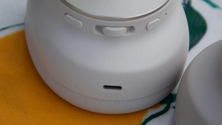 Close-up shot of the ear cup on the Technics EAH-A1000 headphones, highlighting the tactile playback buttons, power switch, and USB-C charging port