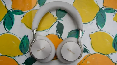 Top-down view of the Technics EAH-A1000 wireless headphones lying flat on a lemon-patterned surface, displaying the silver branded earcups and padded headband