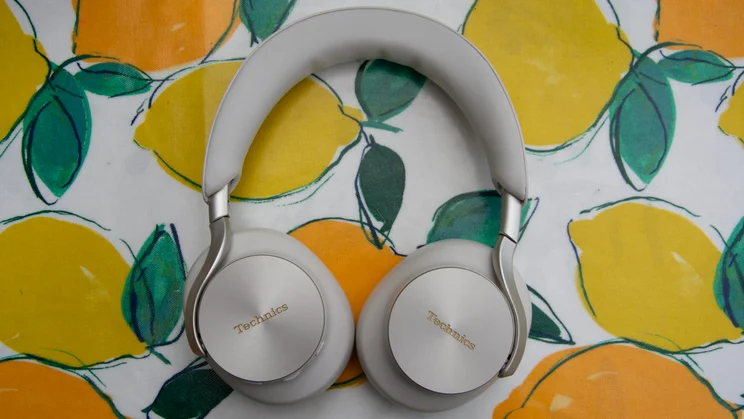 Top-down view of the Technics EAH-A1000 wireless headphones lying flat on a lemon-patterned surface, displaying the silver branded earcups and padded headband