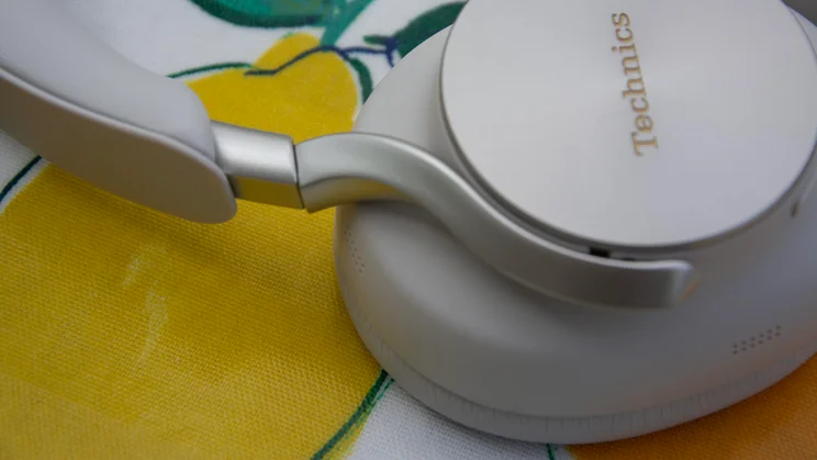 Detailed side angle showing the brushed metal arm and pivot attached to the ear cup featuring the embossed Technics logo on the Technics EAH-A1000