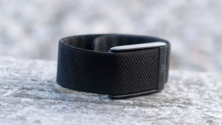 Whoop 5.0 band looped closed on a stone ledge, showing the black woven band and metal case