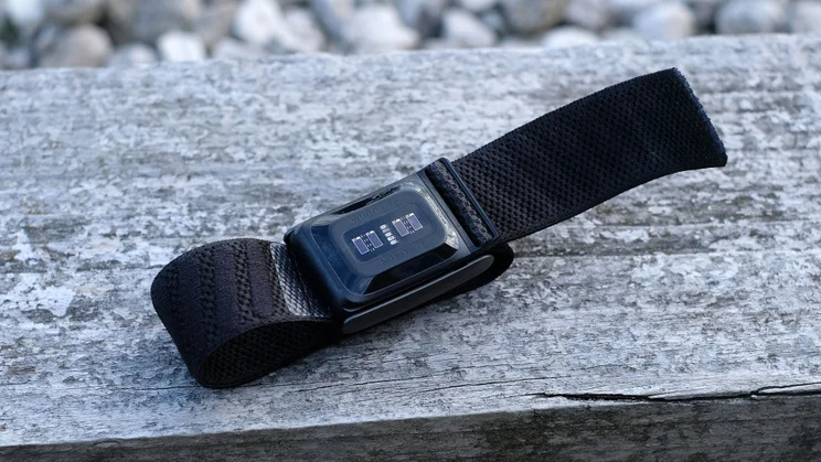 Whoop 5.0 lying on weathered wood with the band unfastened, sensor side facing up