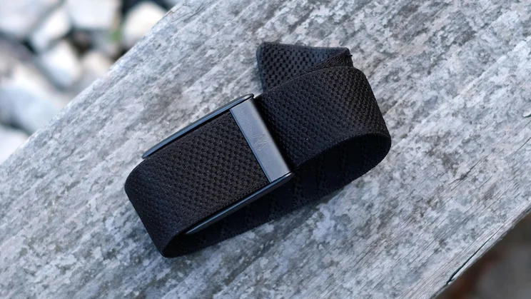 Whoop 5.0 band with its metal case resting on a weathered wooden surface