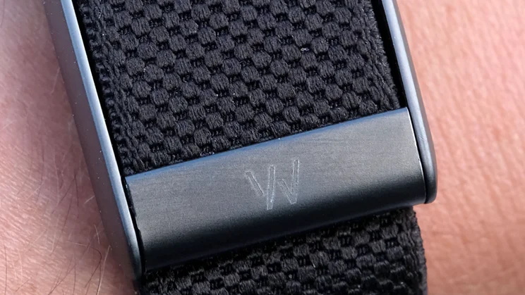 Close-up of the Whoop 5.0 metal case engraved with the Whoop logo, set against the black woven band