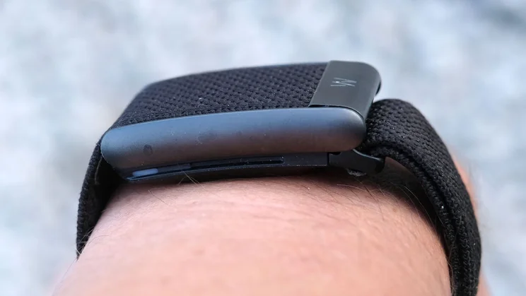 Side profile of a Whoop 5.0 on the wrist, showing the slim pod, sensor window edge and band attachment