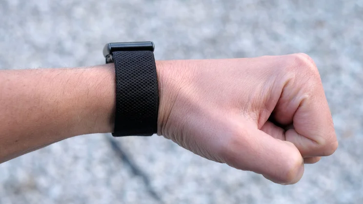 Whoop 5.0 band worn on a wrist with a clenched fist, showing the textured black band from the back of the wrist
