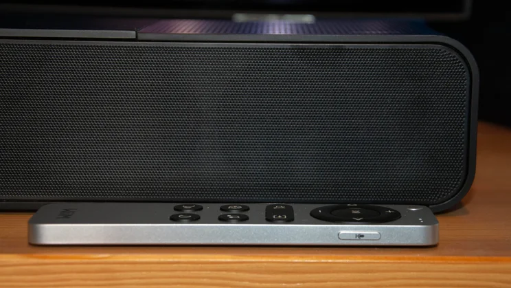 Side profile of the slim silver WiiM Bar remote control resting in front of the black soundbar's mesh grille