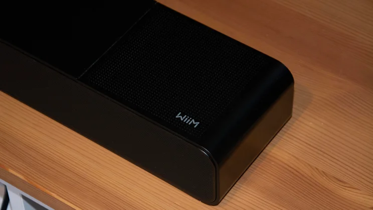 Close-up view of the top-right corner of the WiiM Bar soundbar, showing the top speaker grille panel and the silver WiiM logo