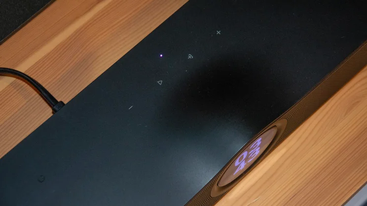 Close-up of the top surface of the WiiM Bar soundbar, highlighting touch control icons for volume and playback